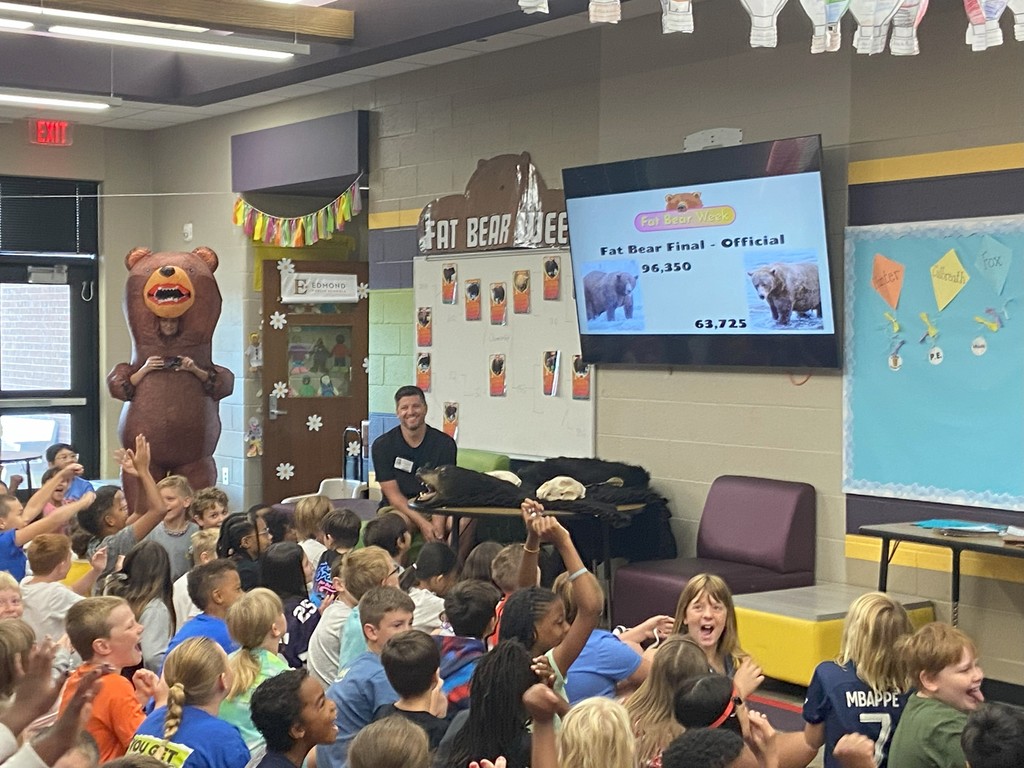 guest speaker with students raising hands and teacher in inflatable bear costume