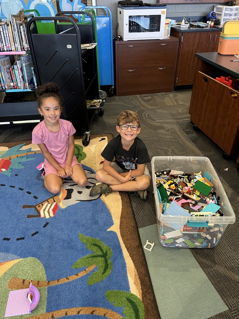 Students smiling next to legos