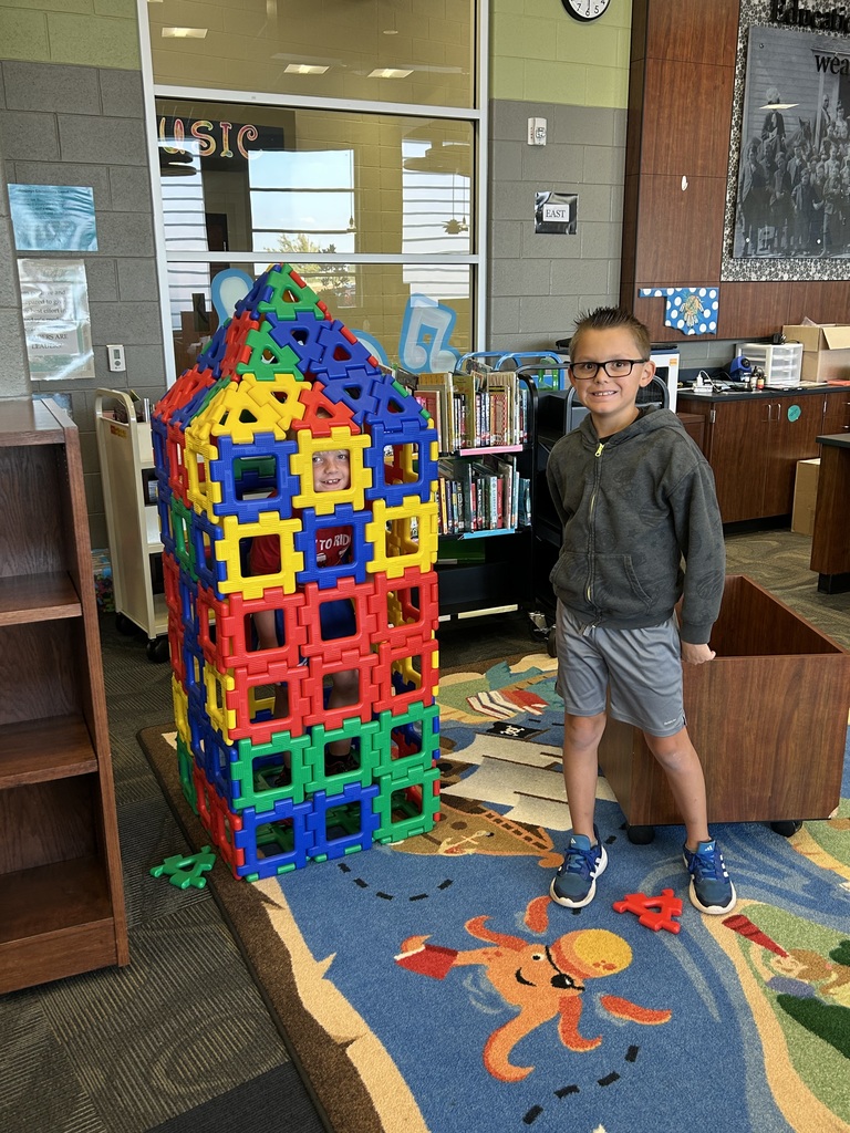 Student standing next to a toy house 
