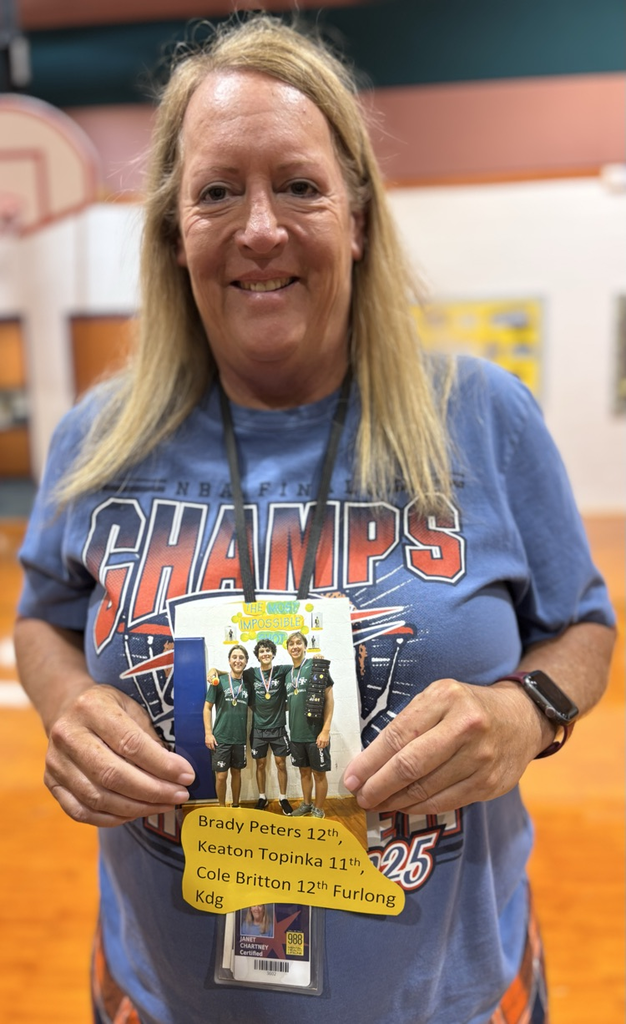 Mrs Chartney holding a picture of high school impossible shot winners 