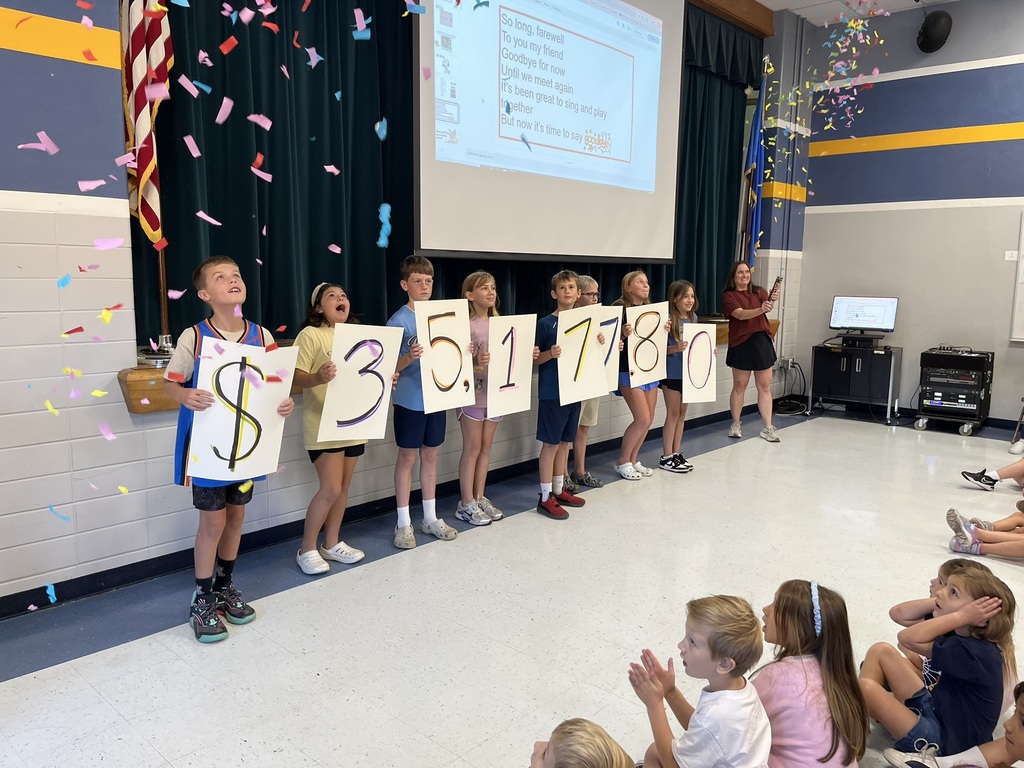 Students reveal fundraiser money earned amid confetti.