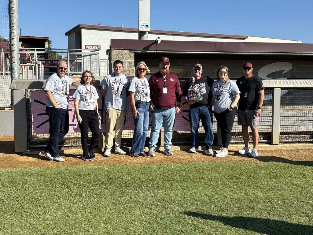 Marcus and Admin  standing with teacher of the year sign 
