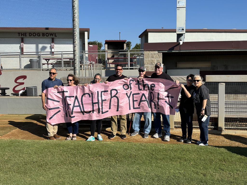 Marcus and family  standing with teacher of the year sign 