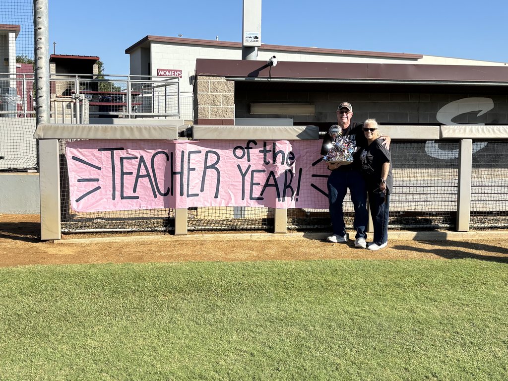 Marcus and wife standing with teacher of the year sign 