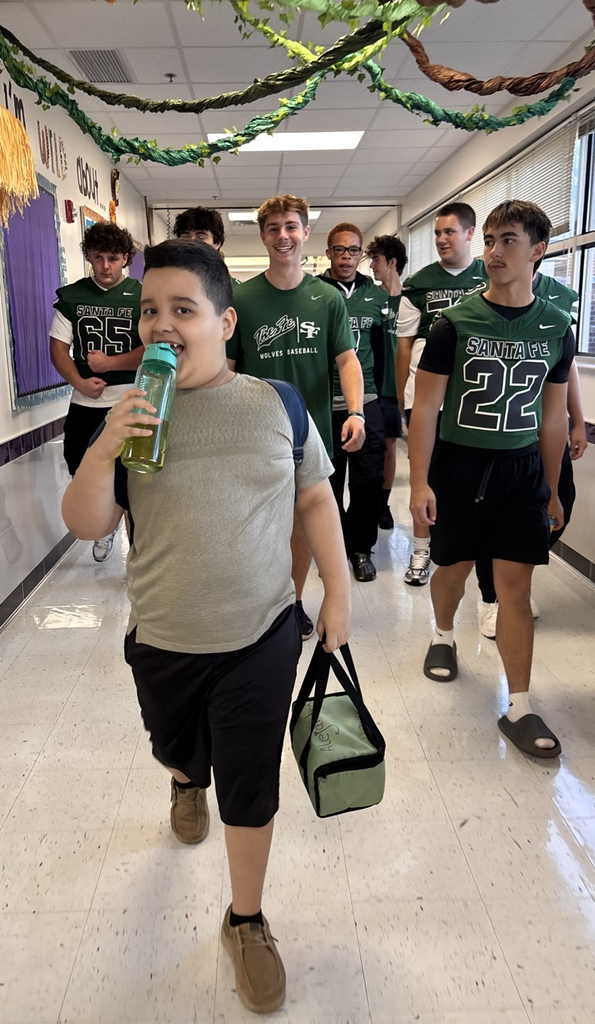 student being walked to class by football team 