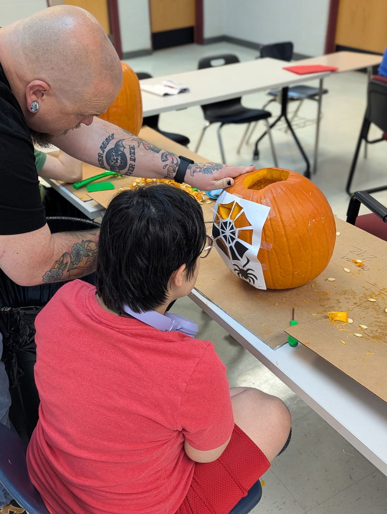An intern and staff carving a pumpkin