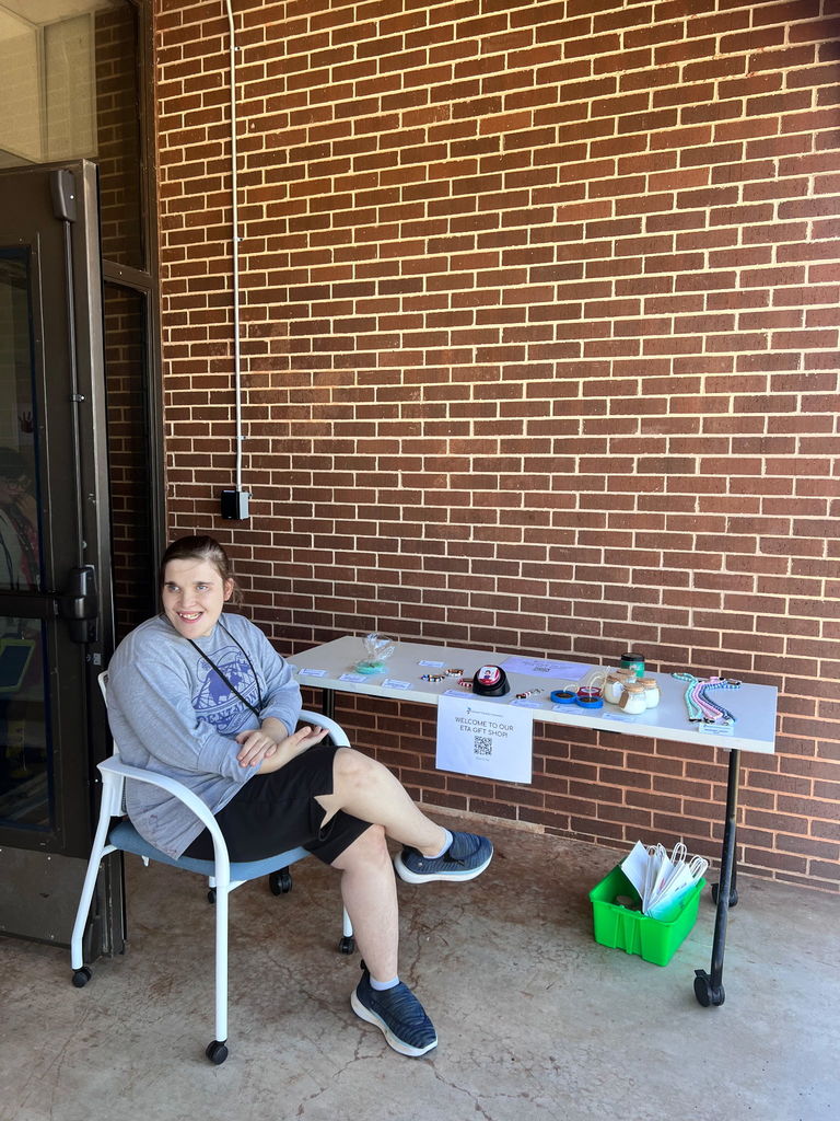 An intern sitting at a table to sell ETA Gift Shop products