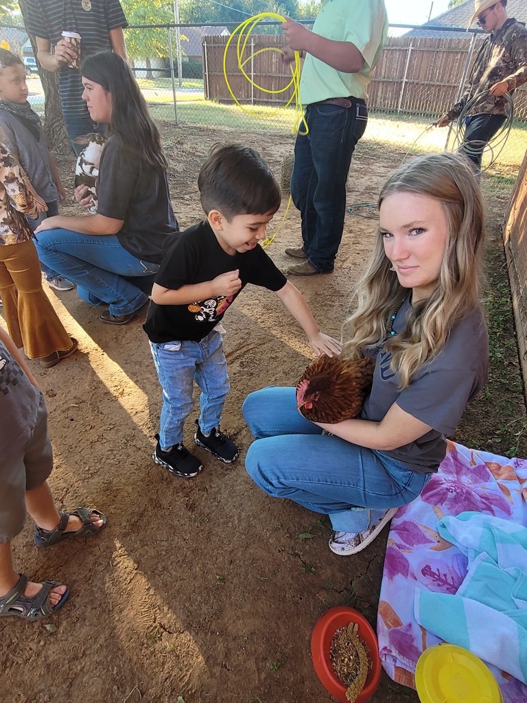 PreK student pets a chicken held by a high school student