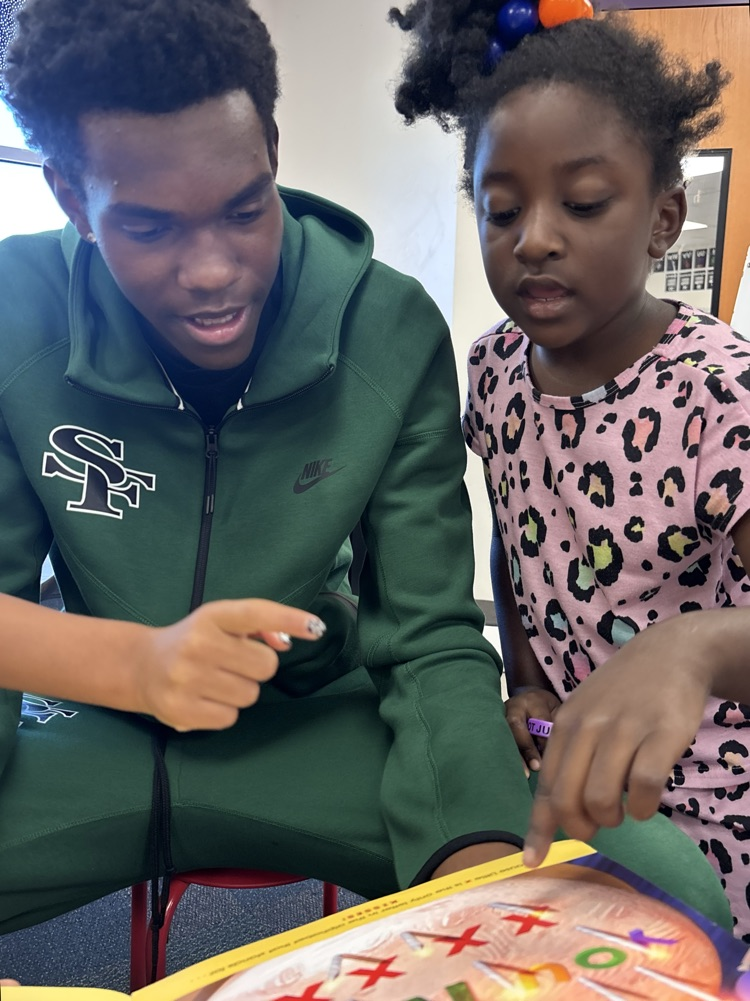 high school basketball player reading with kindergartner 