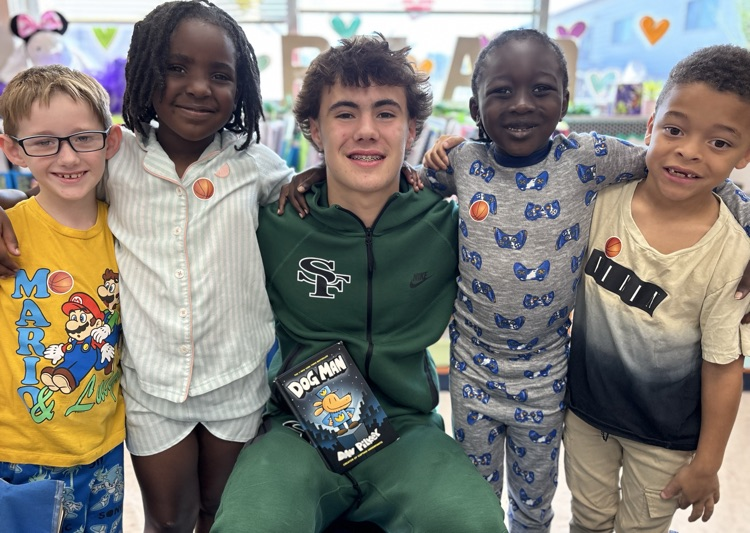 high school basketball player posing with first grade kids 