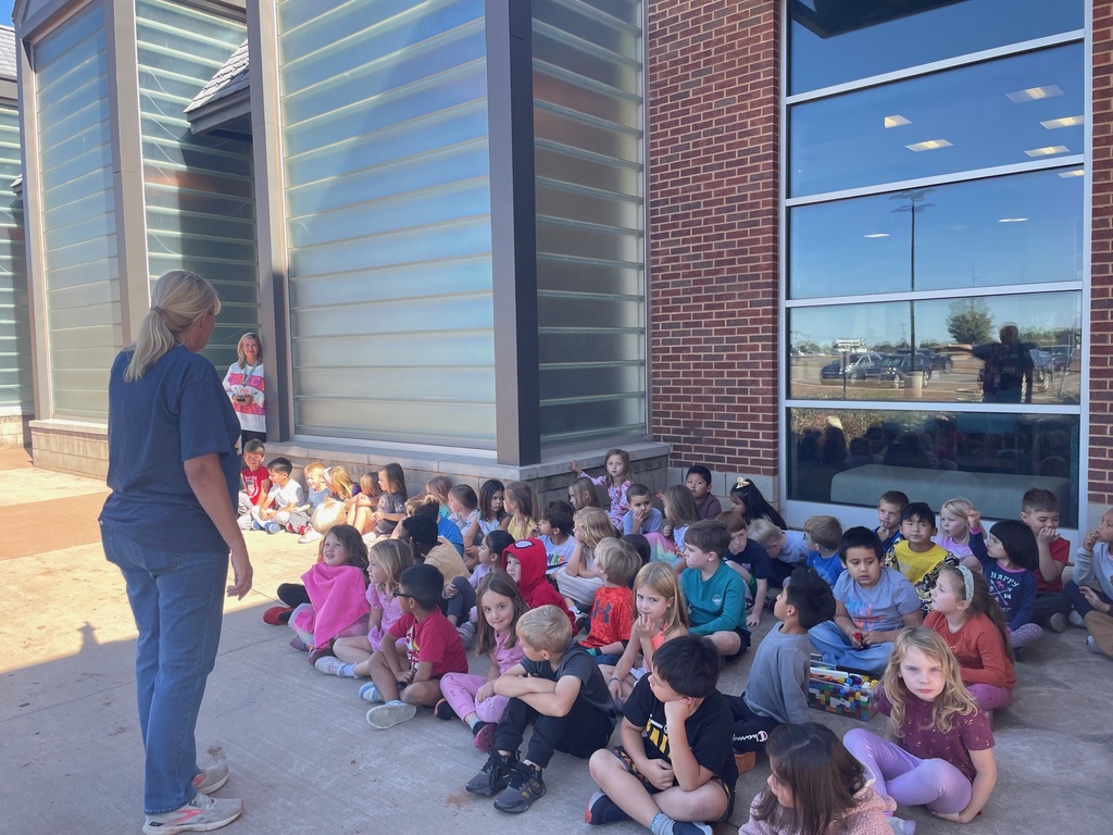 Group of kids sitting listening to woman talking