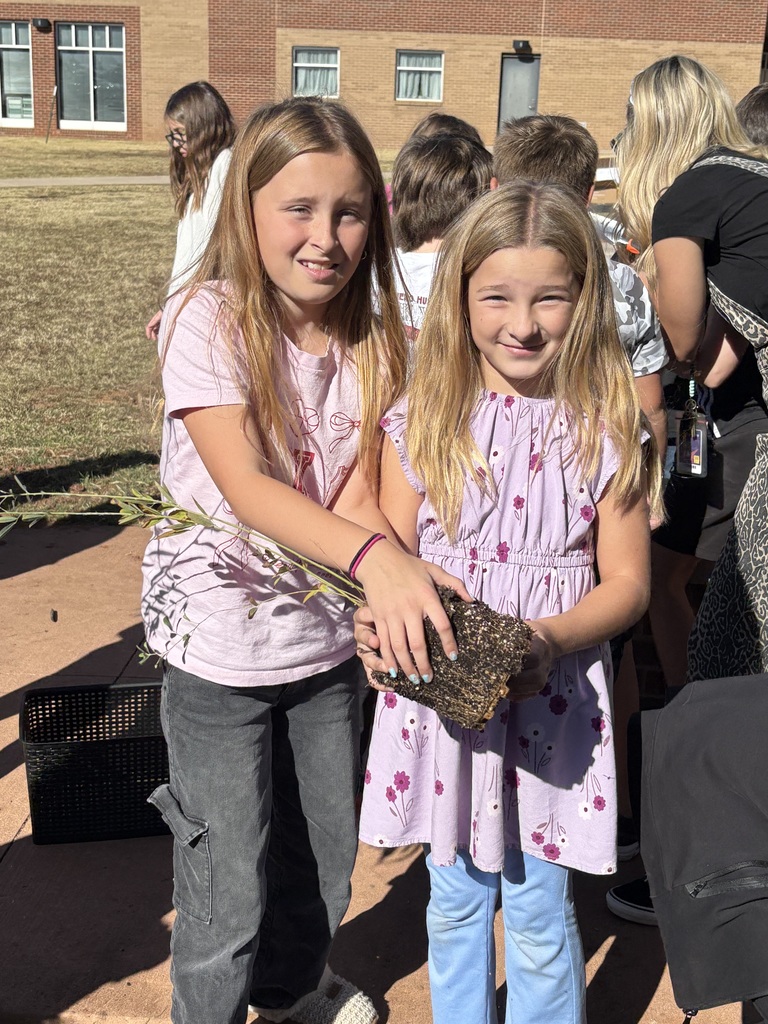 Two girls smiling with a plant