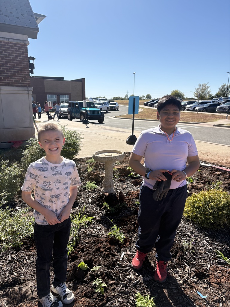 Two boys smiling with a plant