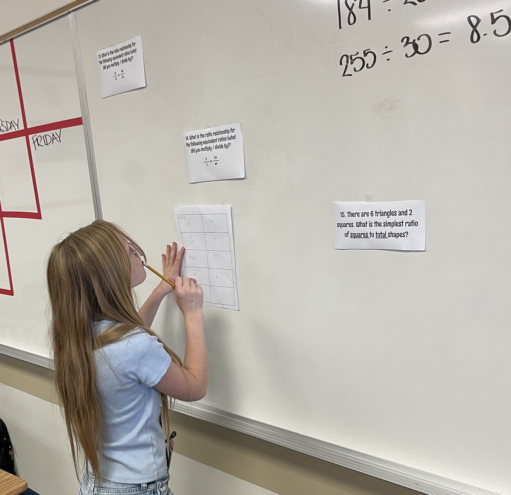 Student looks at math problem posted on dry erase board as part of a review activity.