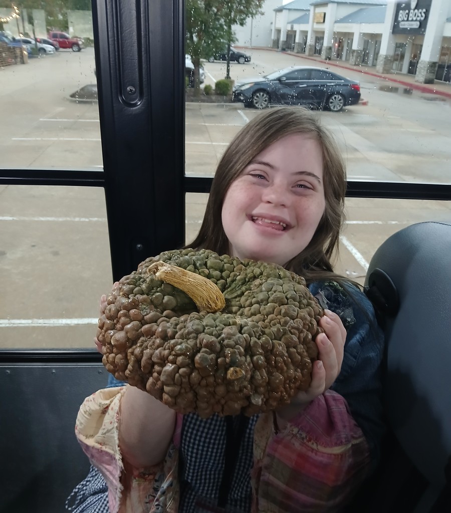 An intern holding the bumpy pumpkin.