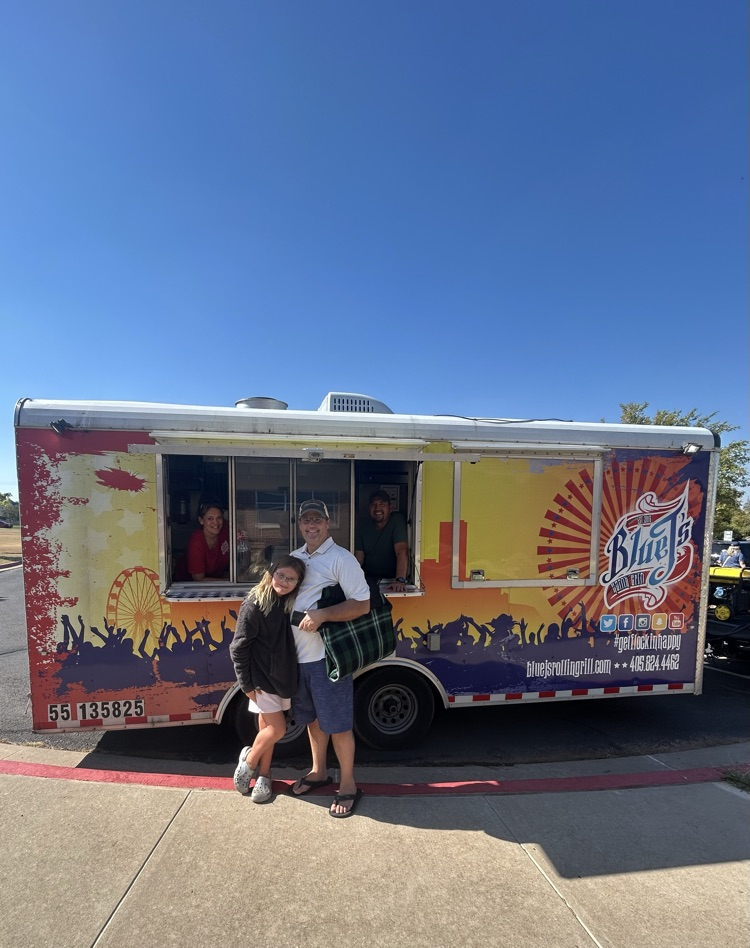 student with parent in front of food truck at cookout 
