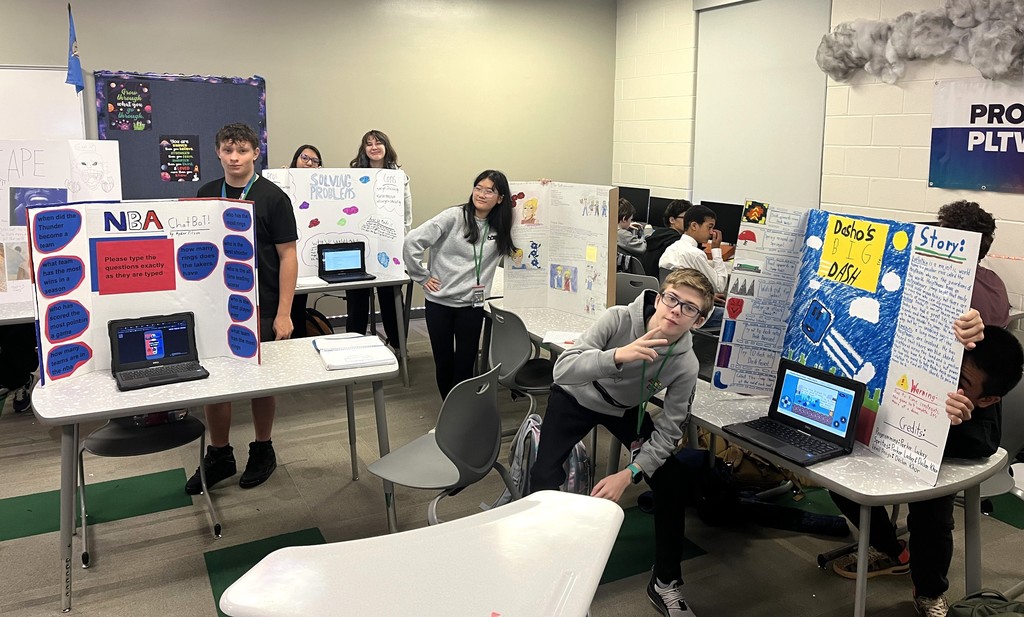 students standing next to their projects