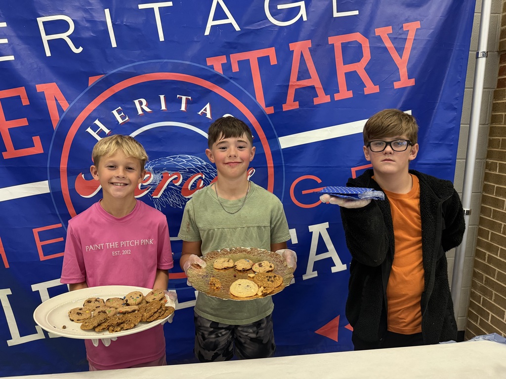 Students smiling next to cookies and cupcakes