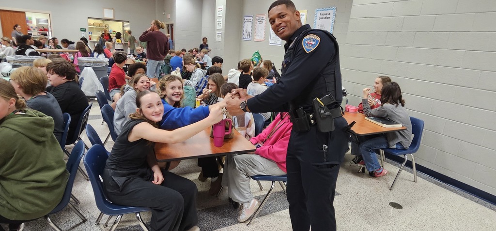 Officer Ross fist bumping two female students in the cafeteria