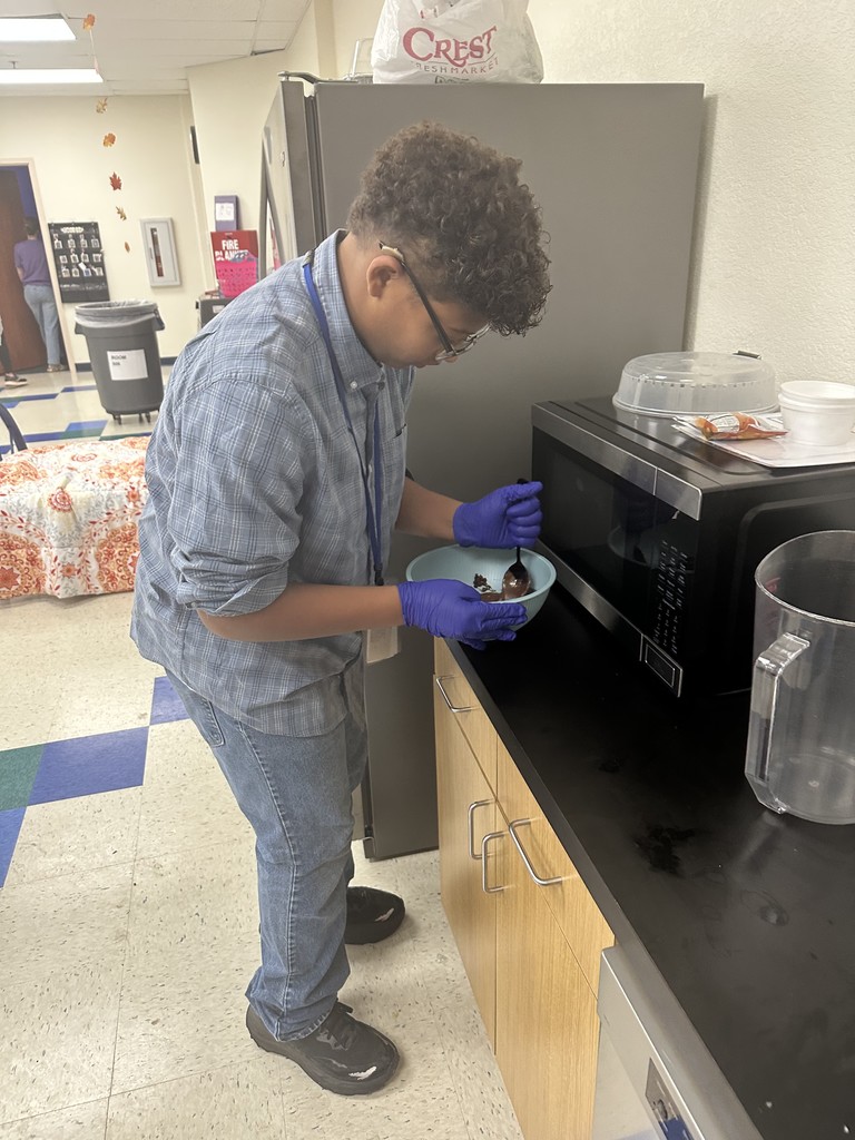 A boy wearing gloves stirring warm chocolate in a bowl
