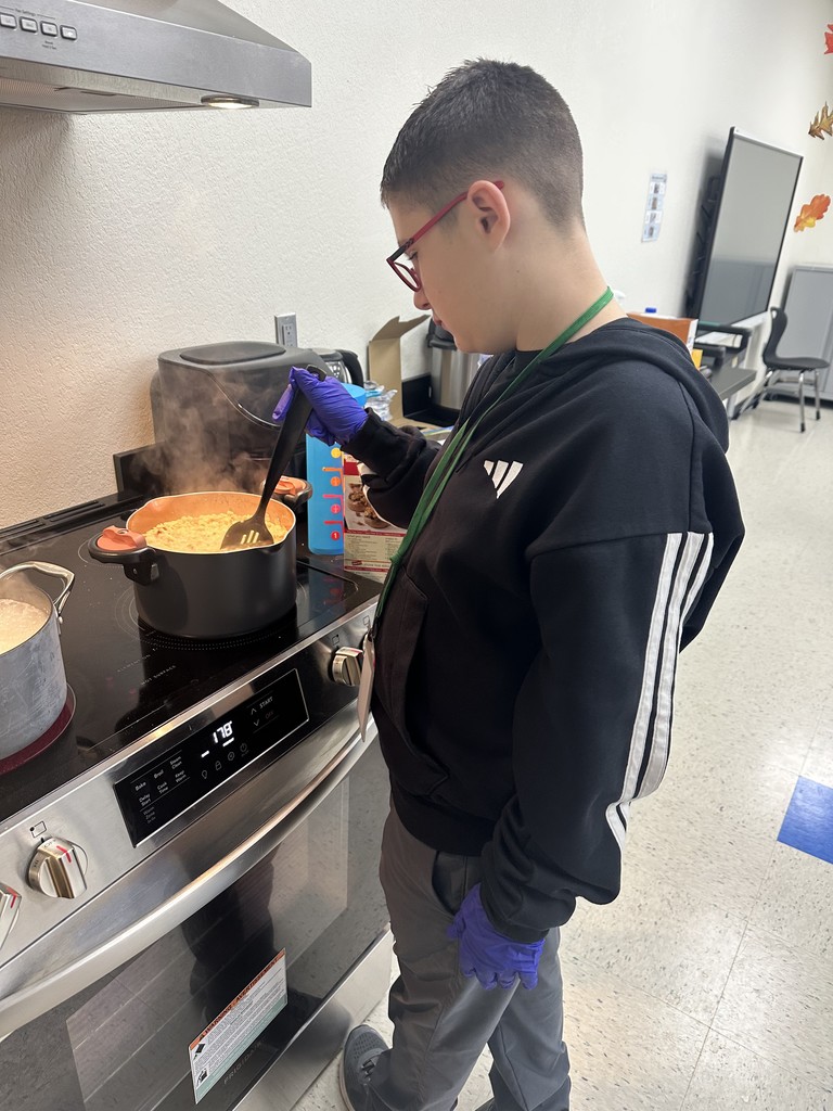 A boy with gloves on stirring a pot of food