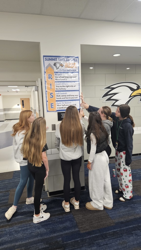 WEB (Where Everyone Belongs) Leaders hang new signage in an 8th grade hallway.