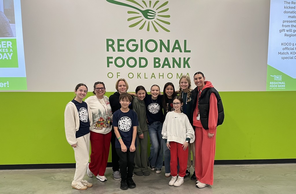 A group of 8 students and 2 teachers standing in front of a wall that says, "Regional Food Bank of Oklahoma."
