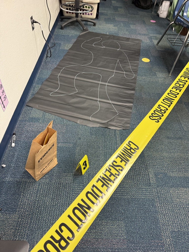 A black piece of paper laying on the ground with a chalk outline of a body, a brown sack, a yellow plastic label with the #3 on it, and crime scene tape