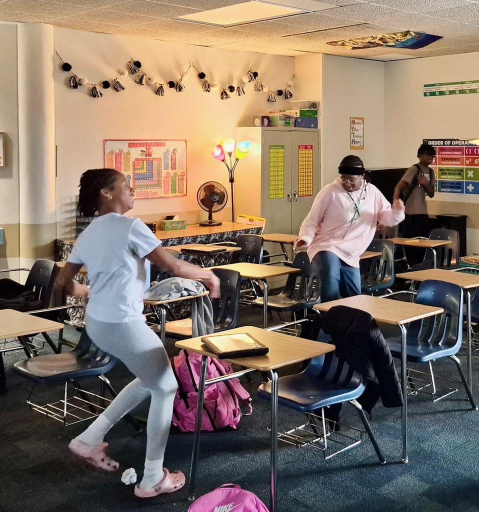 Student smiles while throwing a paper snowball across the room during a review game called math snowball fight.