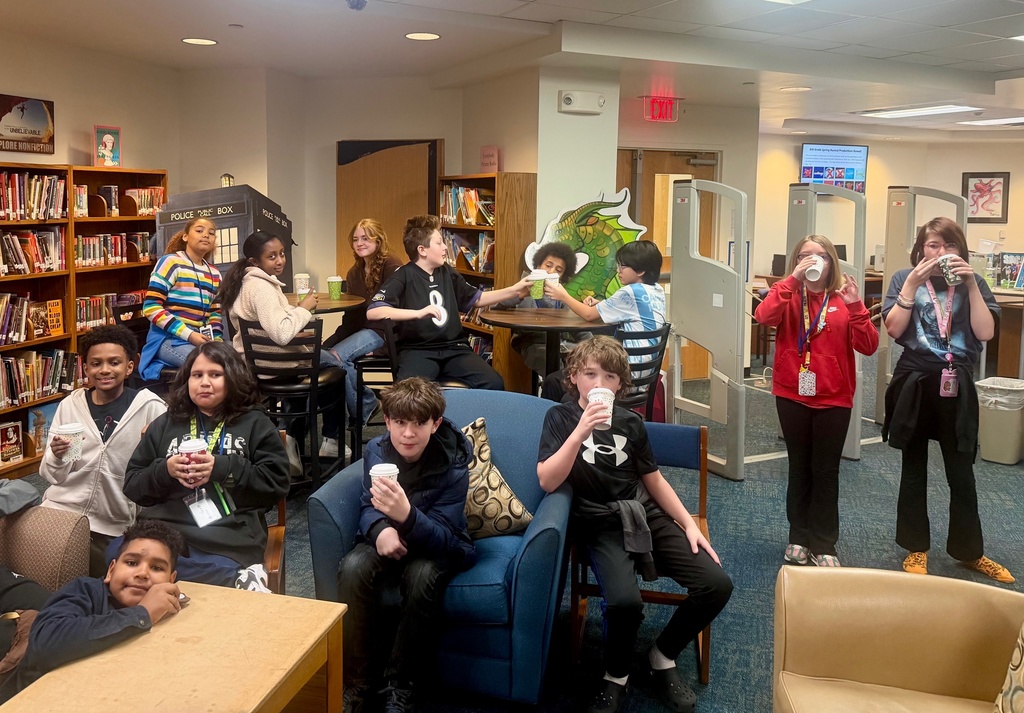 Large group of students sit and sip hot chocolate during Starbooks Book Tasting event in the library.