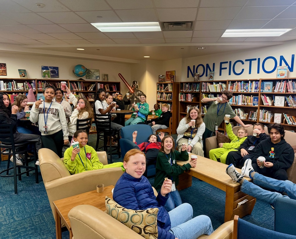 Large group of students sit and sip hot chocolate during Starbooks Book Tasting event in the library.
