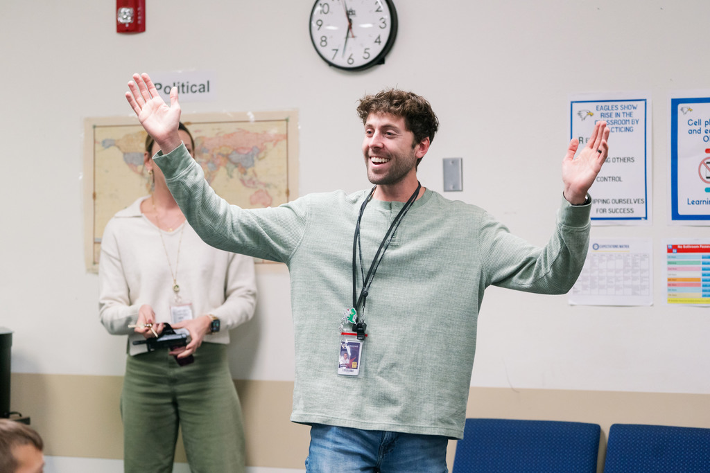 Daniel DeWindt, Summit Teacher of the Year, is pictured smiling with hands raised in shock as he learns that he is one of six finalists for District Teacher of the Year.
