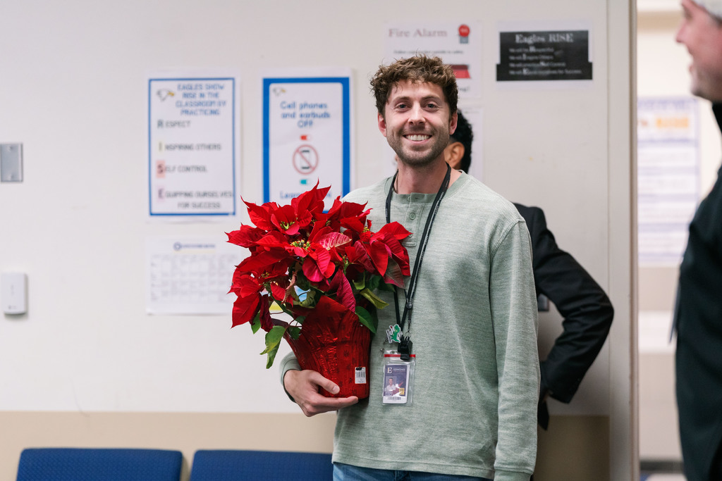 Summit Teacher of the Year, Daniel DeWindt, holds poinsettia after learning that he is a district Teacher of the Year finalist.