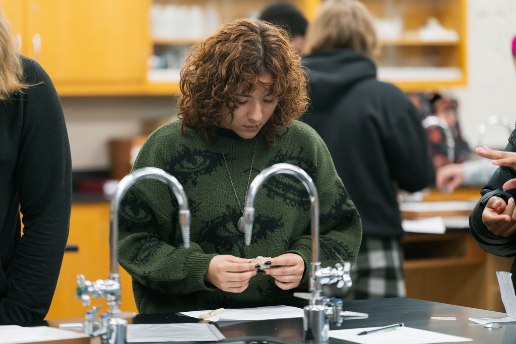 student looking at a rock in a lab