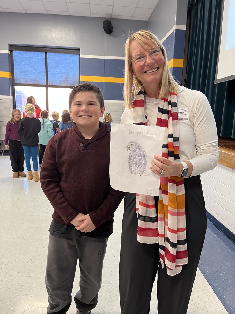Author Kristin Tubb is given a drawing of an African Gray Parrot by a fourth grade student.