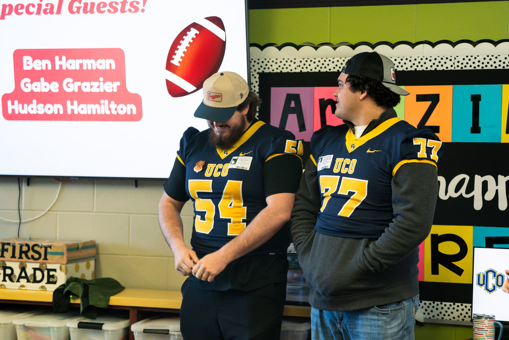 football players talking to elementary students