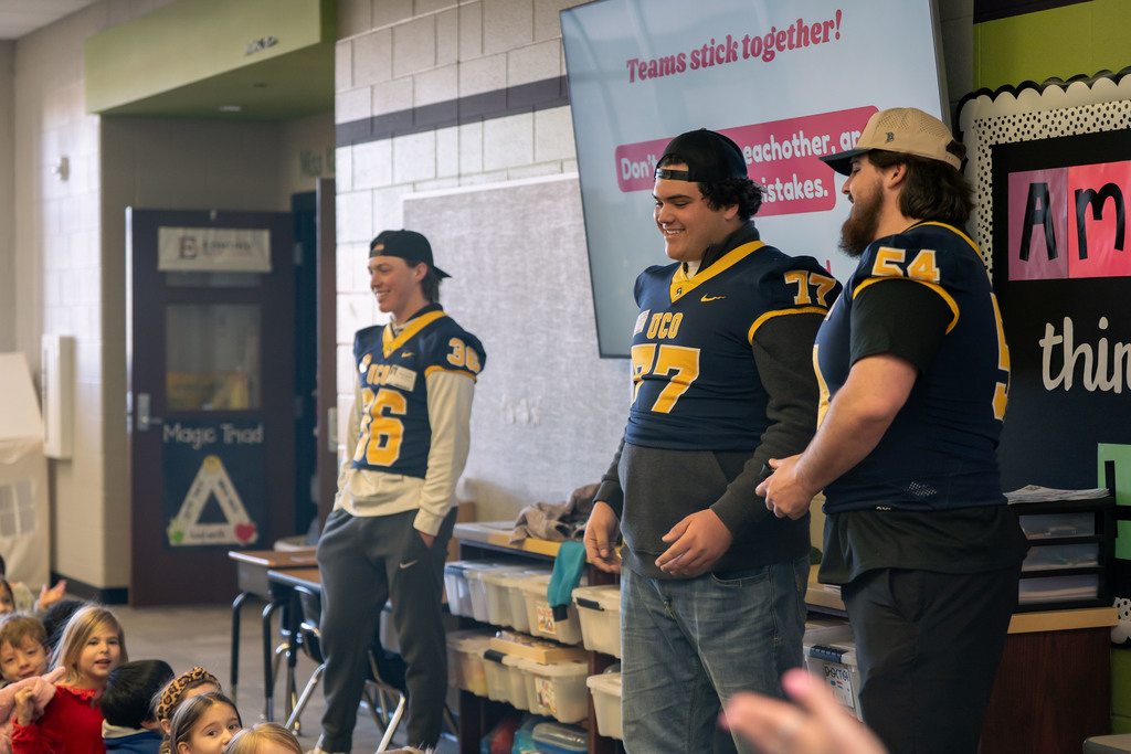 football players talking to elementary students