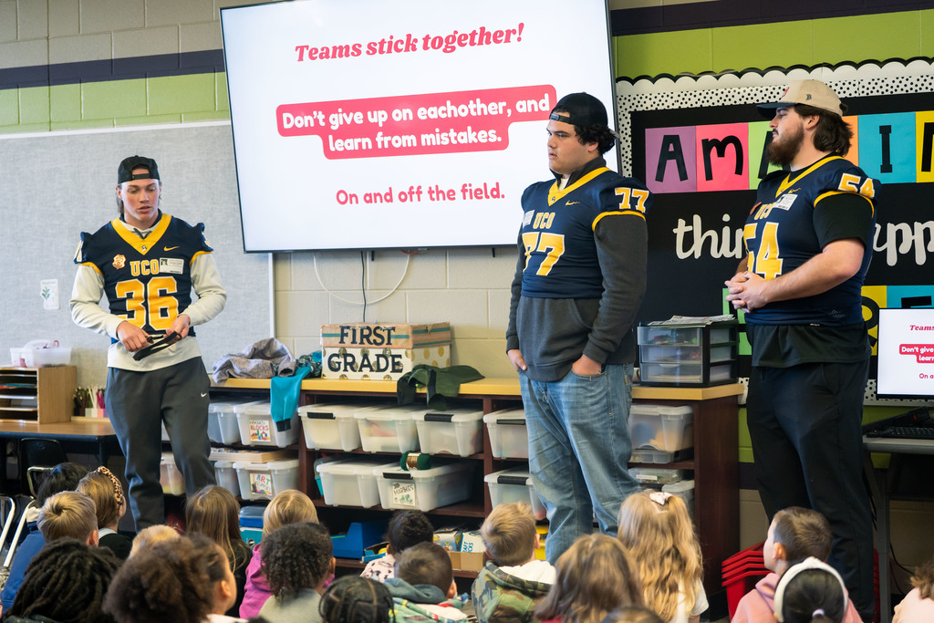 football players talking to elementary students