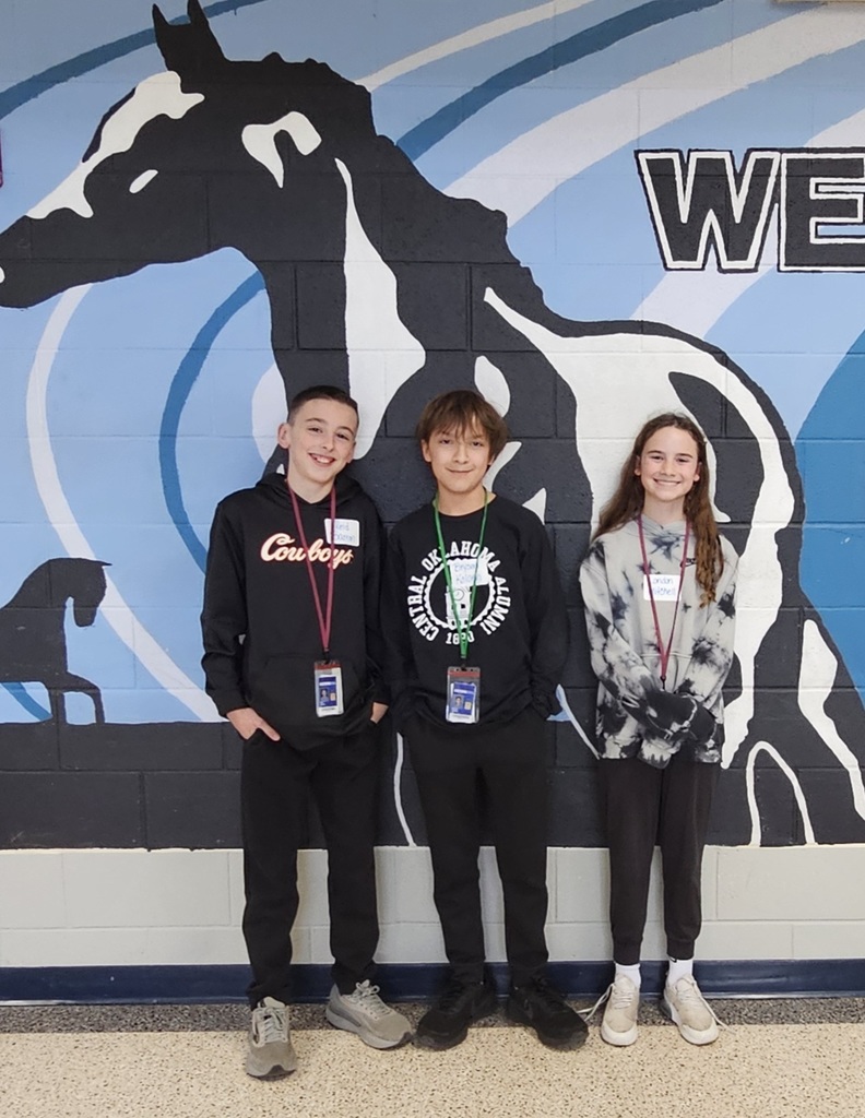 Two boys and a girl posing in front of the mustang mural
