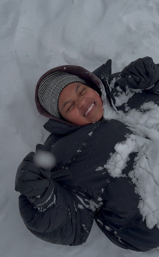 student lying in the snow