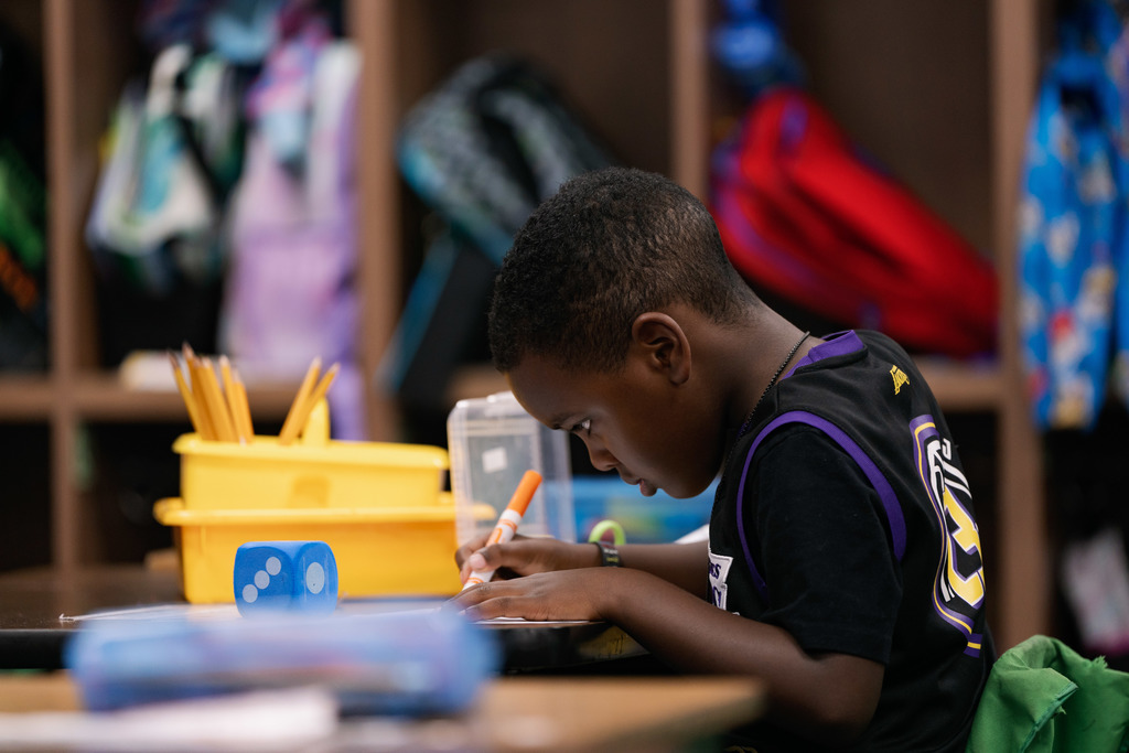 boy writing something down at her desk