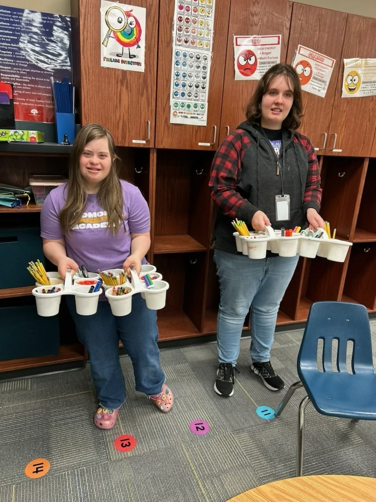 Interns supporting a classroom teacher preparing supplies for a student project. 