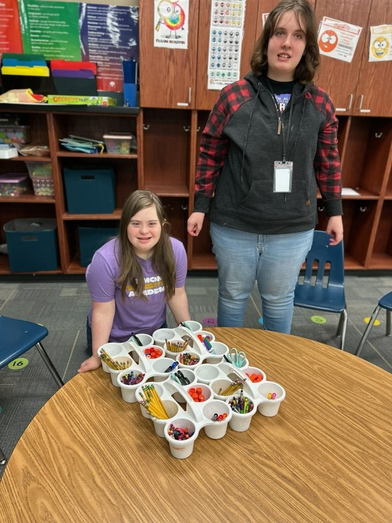 Interns supporting a classroom teacher preparing supplies for a student project. 