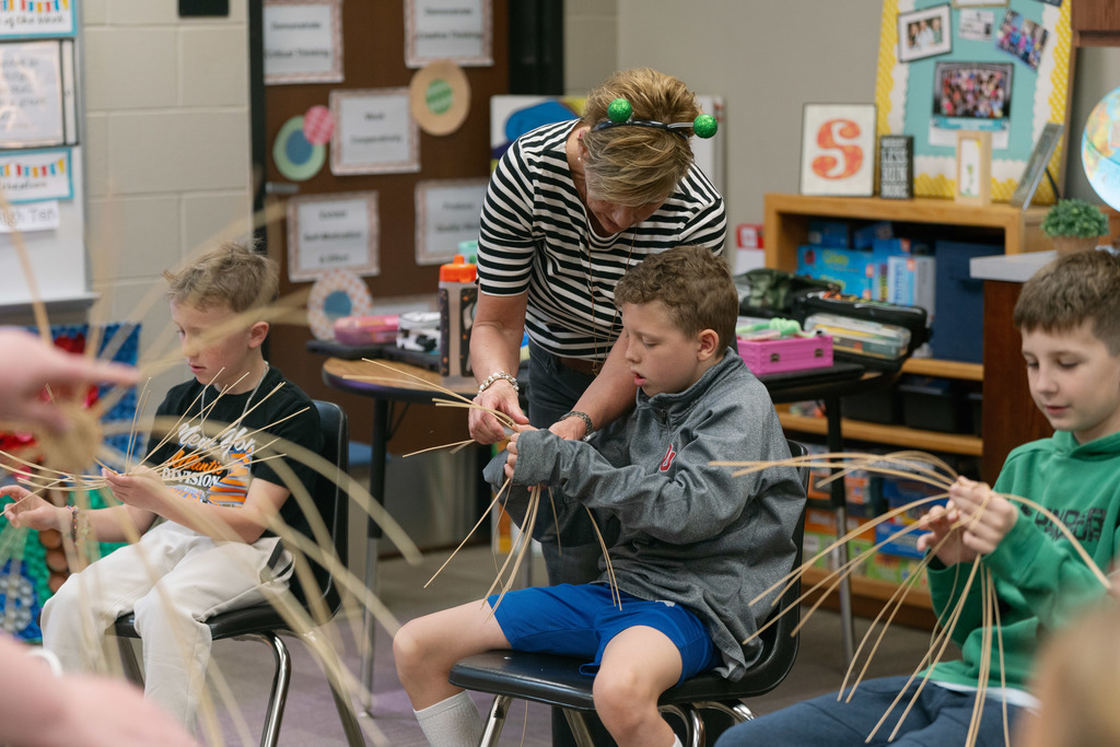 students and their teacher weaving baskets in a classroom
