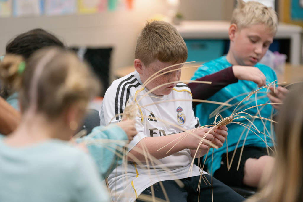 students weaving baskets in a classroom