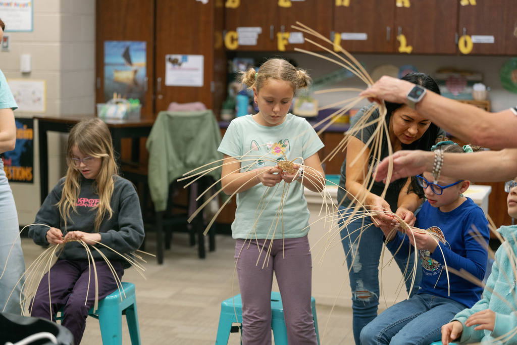 students weaving baskets in a classroom