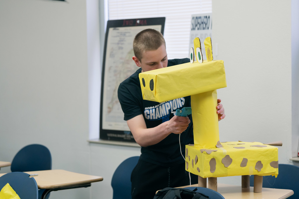 boy putting spots on a hand made giraffe