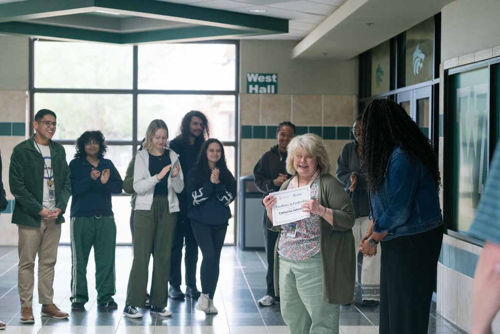 woman being surprised with an award in a high school
