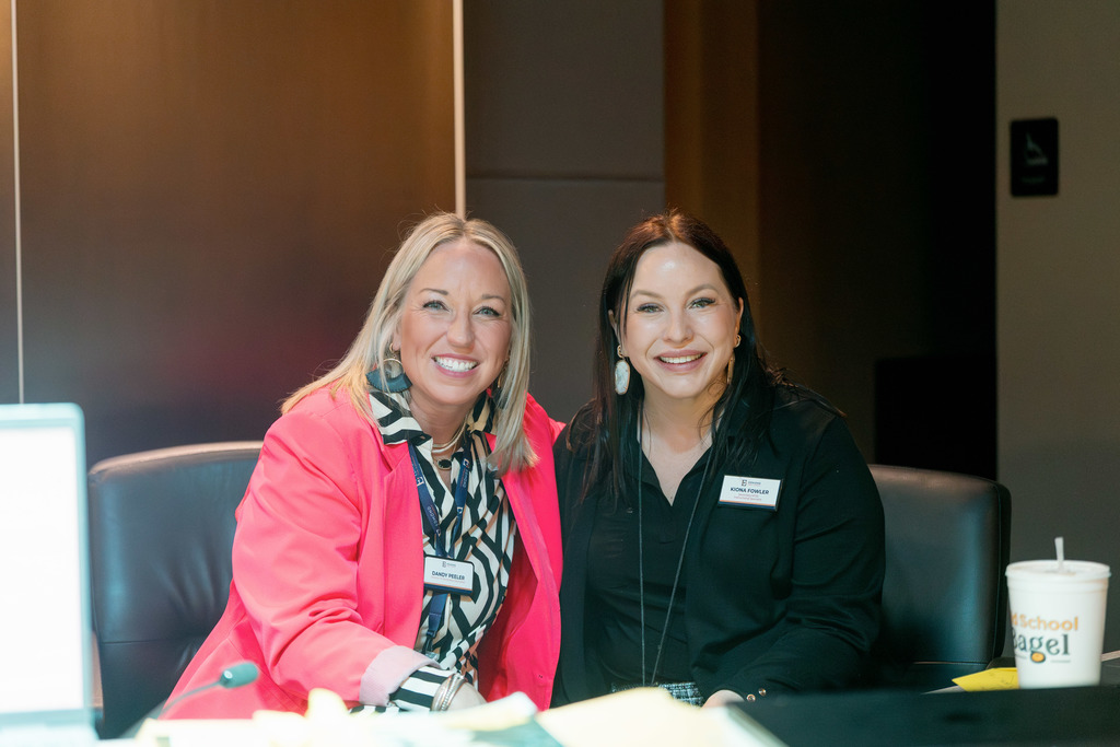 2 women sitting down smiling