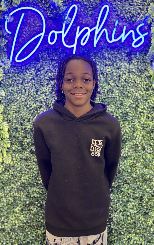student in front of green backdrop with neon sign
